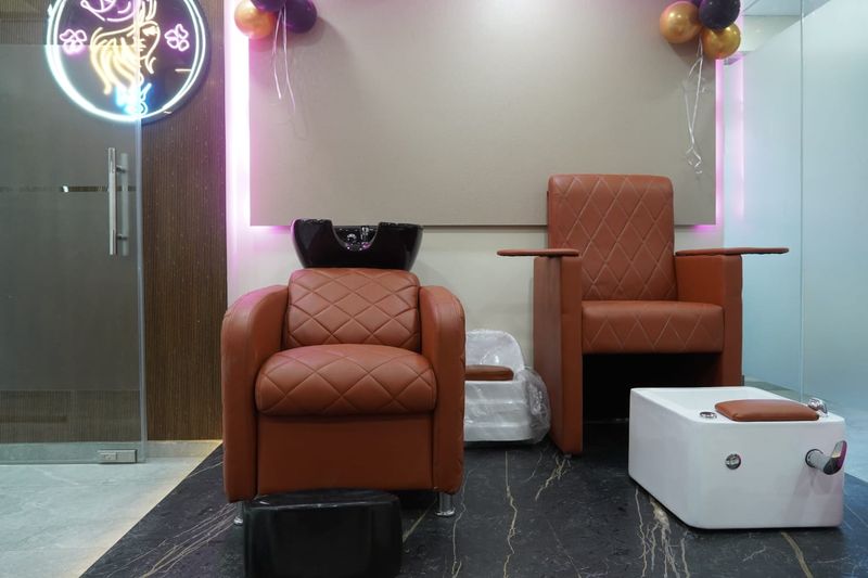 Hair-wash chair and pedicure chair under a soft pink light