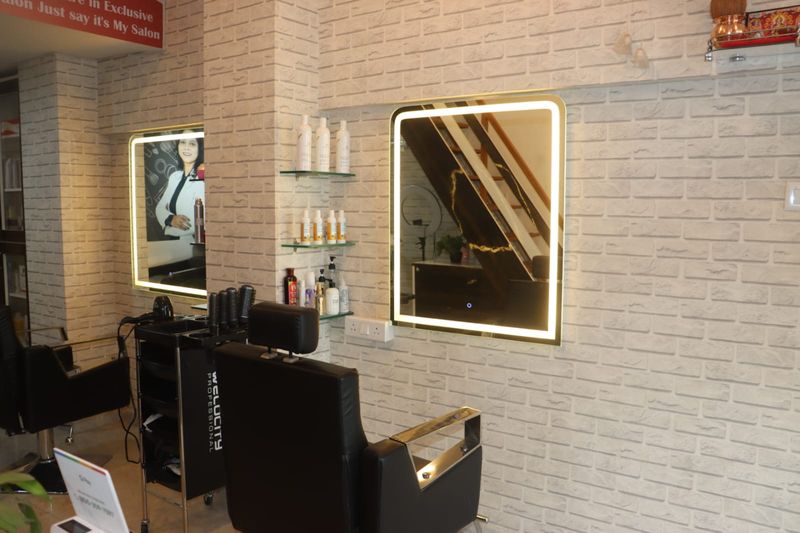 Black styling chairs at backlit mirrors on a white brick wall