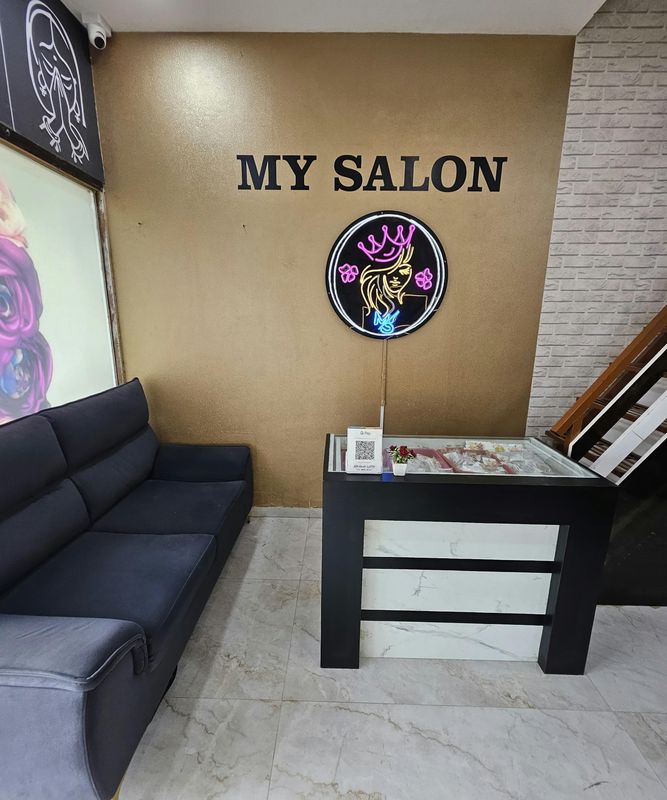 The My Salon reception with the logo on a gold wall and a black sofa