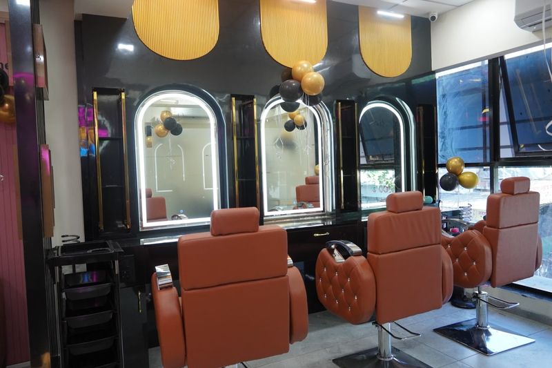 Tan leather styling chairs in front of arched, lit mirrors
